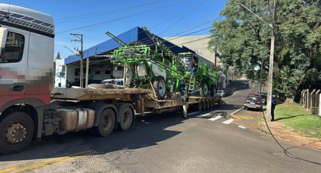 Caminhão que transportava máquina agrícola enrosca em fios e interdita cruzamento