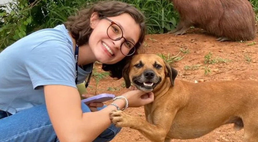 Cachorro caramelo sorri e faz pose em foto com universitária e capivara