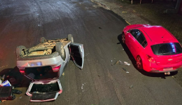 Carro bate em veículo estacionado e capota em avenida de SC