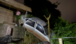 Carro sai da pista, desce barranco e atinge muro de residência