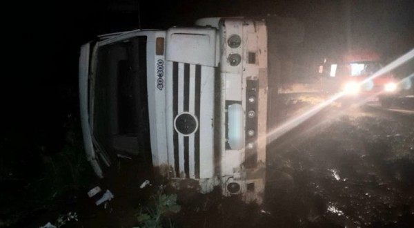 Motorista e passageiro ficam feridos após carreta sair da pista e tombar