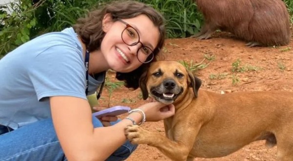 Cachorro caramelo sorri e faz pose em foto com universitária e capivara